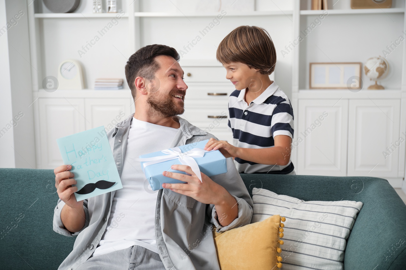 Photo of Happy Father's Day. Son giving his dad card and present at home