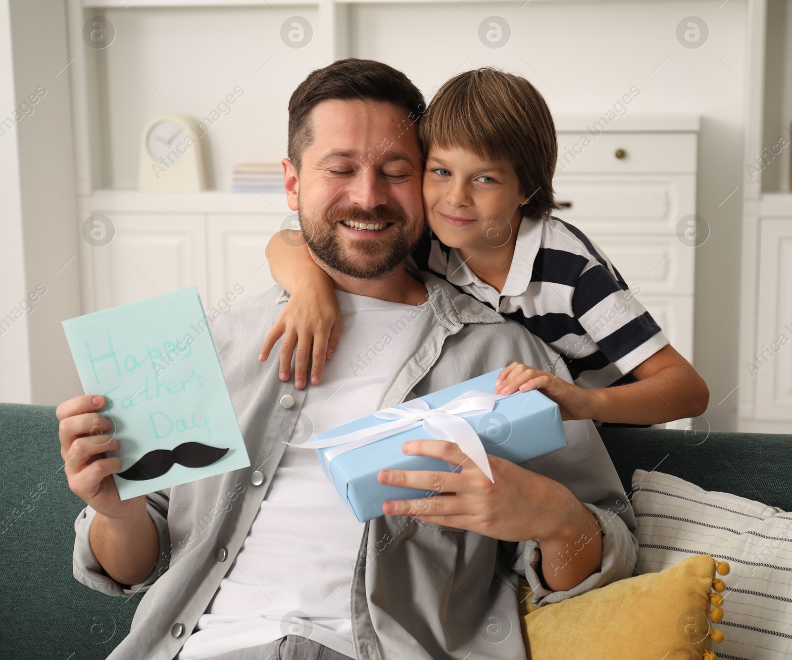 Photo of Happy Father's Day. Son giving his dad card and present at home