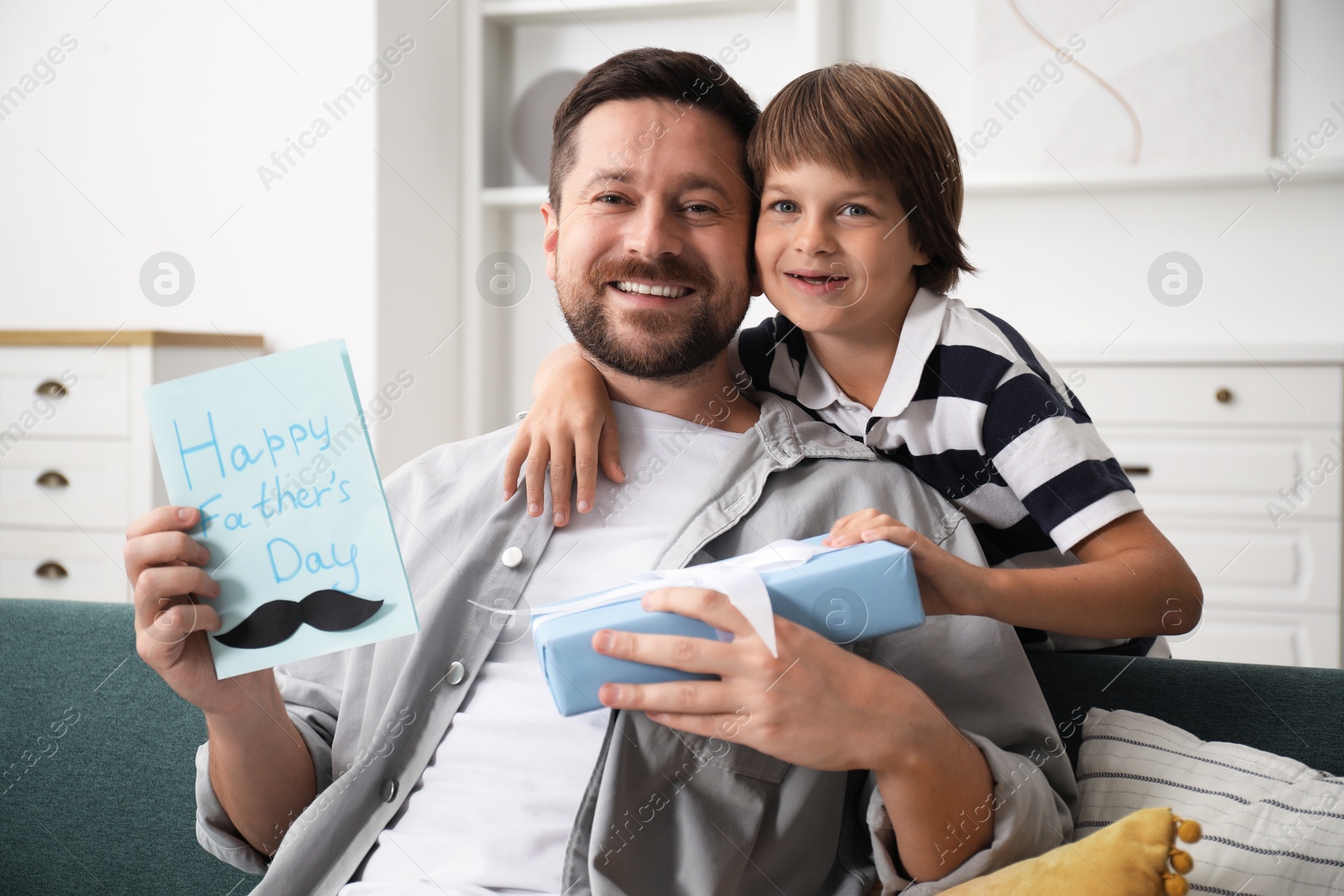 Photo of Happy Father's Day. Son giving his dad card and present at home