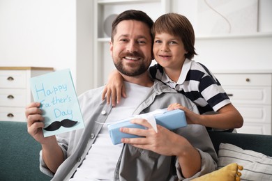 Photo of Happy Father's Day. Son giving his dad card and present at home