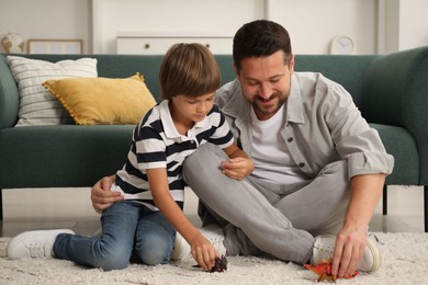 Photo of Father and son playing with dinosaur toys at home