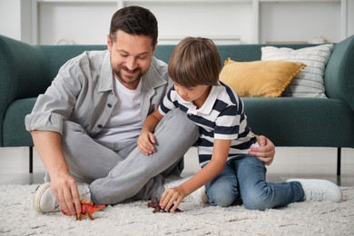 Photo of Father and son playing with dinosaur toys at home