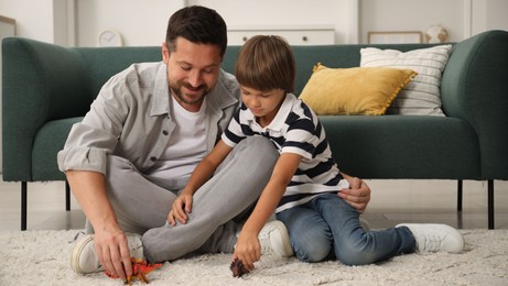 Photo of Father and son playing with dinosaur toys at home