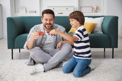 Photo of Father and son playing with dinosaur toys at home