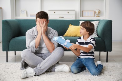 Photo of Happy Father's Day. Son giving his dad gift at home