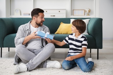 Photo of Happy Father's Day. Son giving his dad gift at home