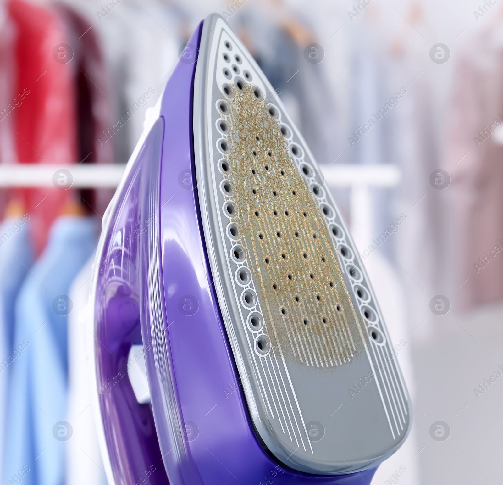 Image of Clothes iron soleplate with burnt residue and scale indoors, closeup