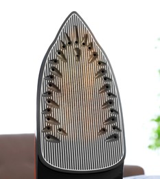 Image of Clothes iron soleplate with burnt residue and scale indoors, closeup