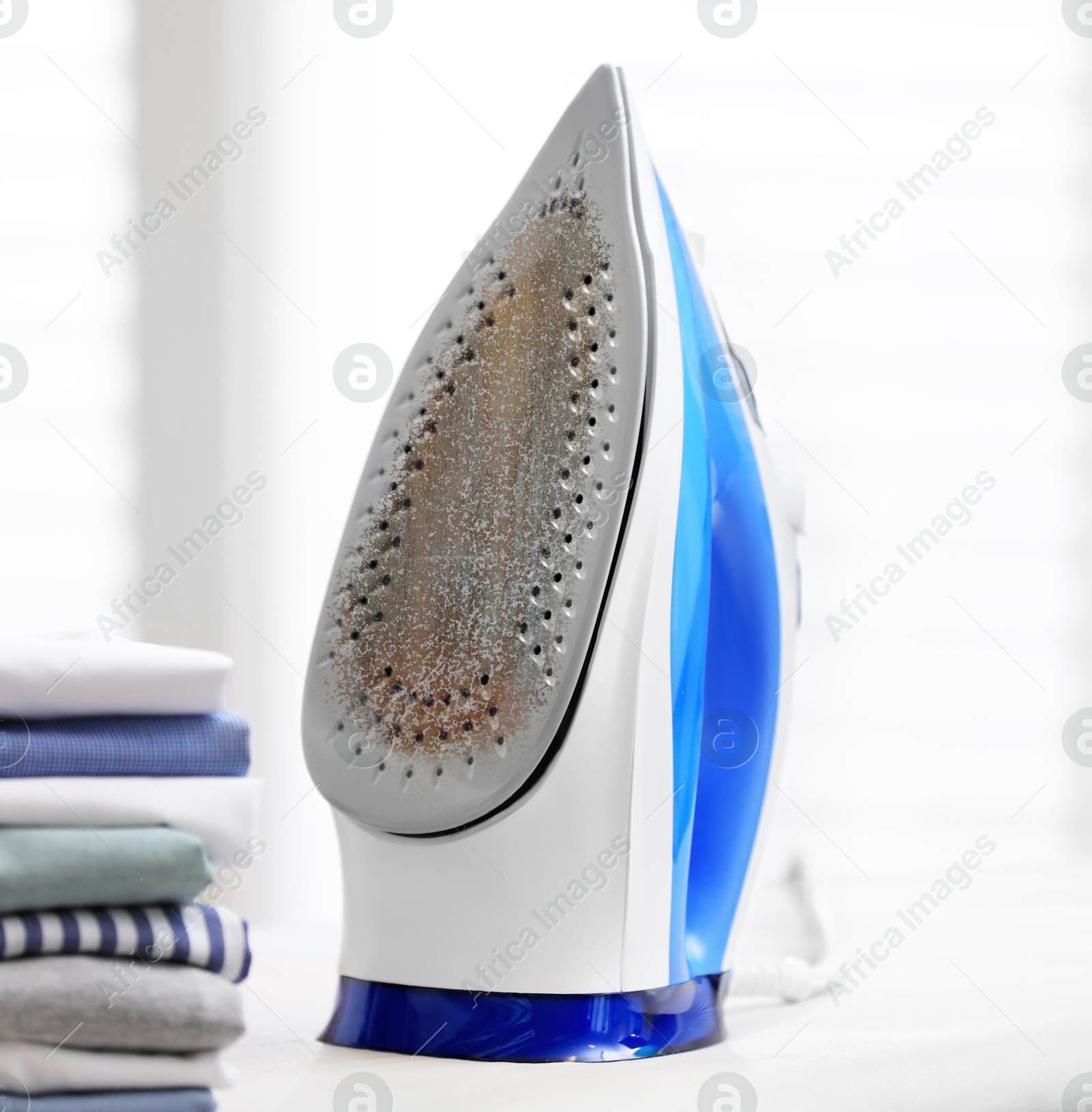 Image of Clothes iron soleplate with burnt residue and scale indoors, closeup