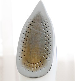 Image of Clothes iron soleplate with burnt residue and scale indoors, closeup