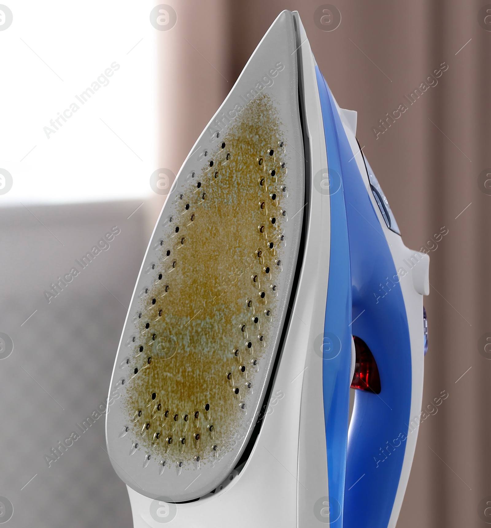 Image of Clothes iron soleplate with burnt residue and scale indoors, closeup