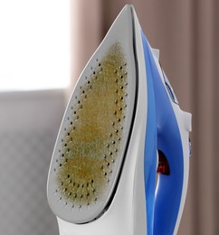 Image of Clothes iron soleplate with burnt residue and scale indoors, closeup