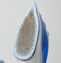 Image of Clothes iron soleplate with burnt residue and scale against light background, closeup