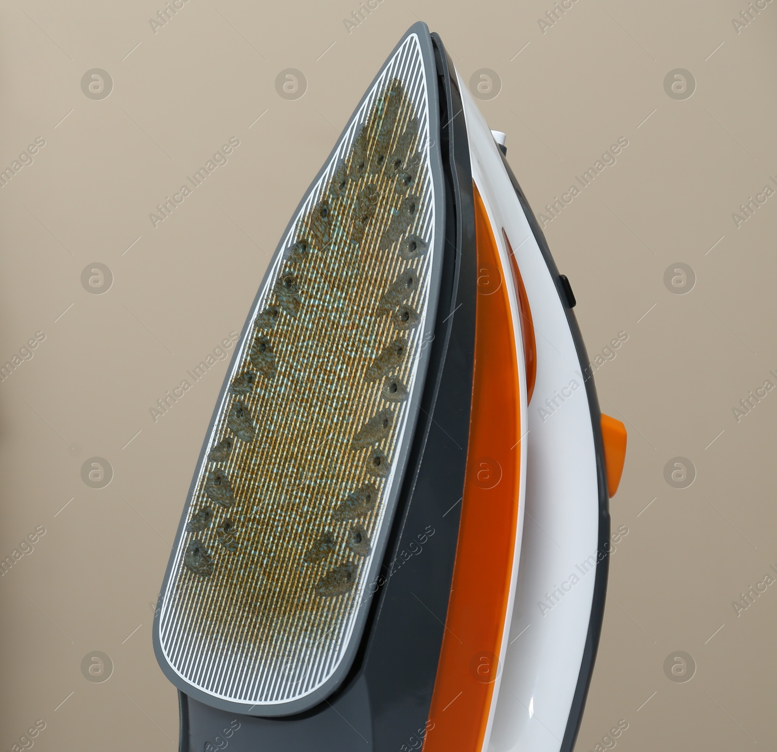 Clothes iron soleplate with burnt residue and scale against dark beige background, closeup Image of Clothes iron soleplate with burnt residue and scale against dark beige background, closeup