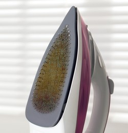 Image of Clothes iron soleplate with burnt residue and scale indoors, closeup