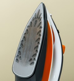 Image of Clothes iron soleplate with burnt residue and scale against beige background, closeup