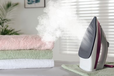 Image of Steam coming out of clothes iron and towels indoors