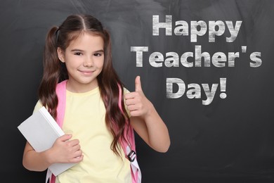 Image of Happy Teacher's Day. Cute little girl showing thumbs-up near blackboard