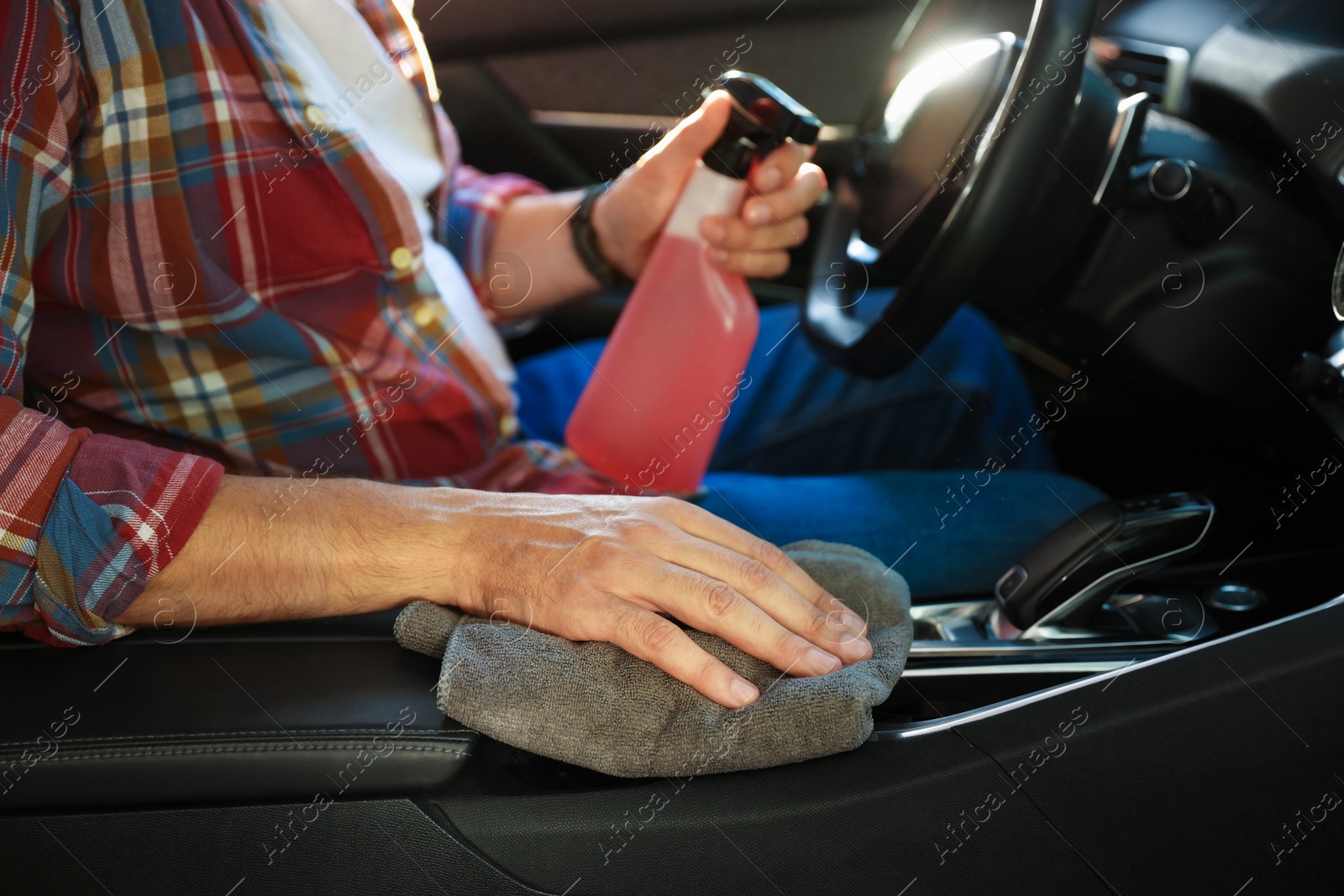 Man wiping car center console with grey microfiber rag in salon, closeup Photo of Man wiping car center console with grey microfiber rag in salon, closeup