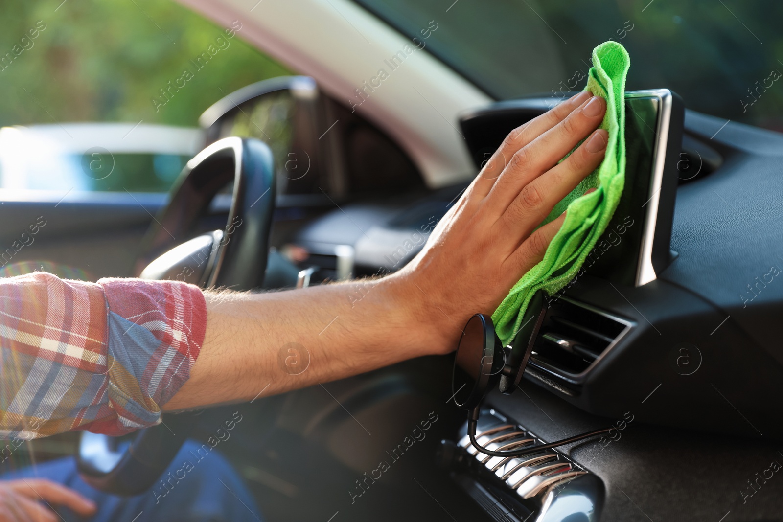 Man wiping car dashboard with green microfiber rag in salon, closeup Photo of Man wiping car dashboard with green microfiber rag in salon, closeup