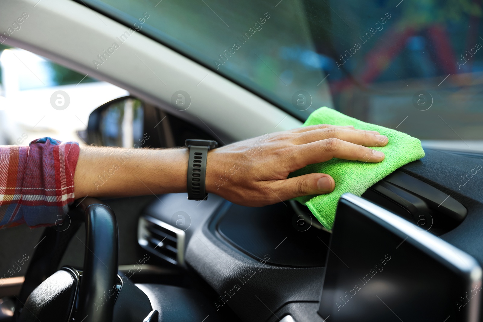 Man wiping car dashboard with green microfiber rag in salon, closeup Photo of Man wiping car dashboard with green microfiber rag in salon, closeup
