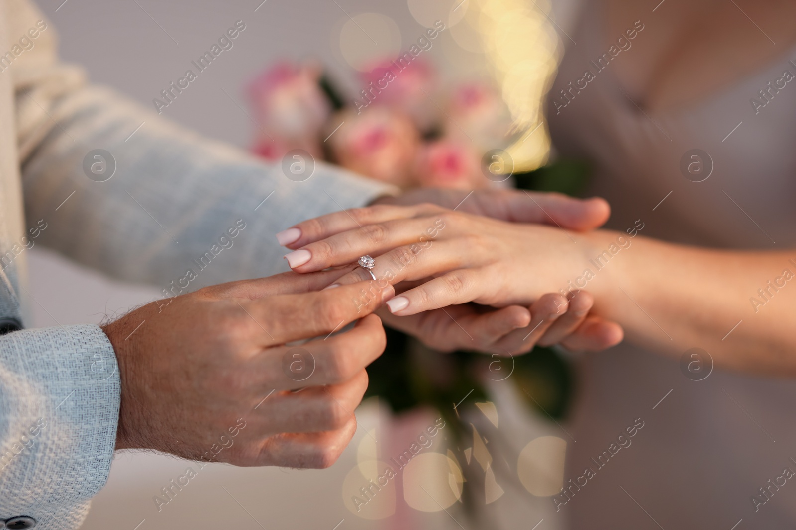 Making marriage proposal. Man putting engagement ring on his girlfriend's finger against blurred background, closeup. Bokeh effect Photo of Making marriage proposal. Man putting engagement ring on his girlfriend's finger against blurred background, closeup. Bokeh effect
