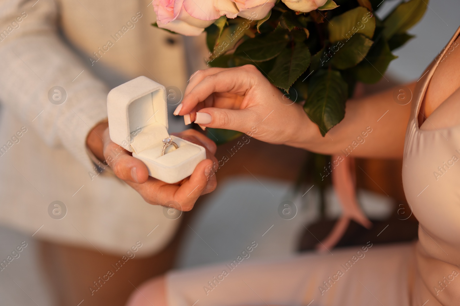 Photo of Man with engagement ring and bouquet of flowers making marriage proposal to his girlfriend on blurred background, closeup
