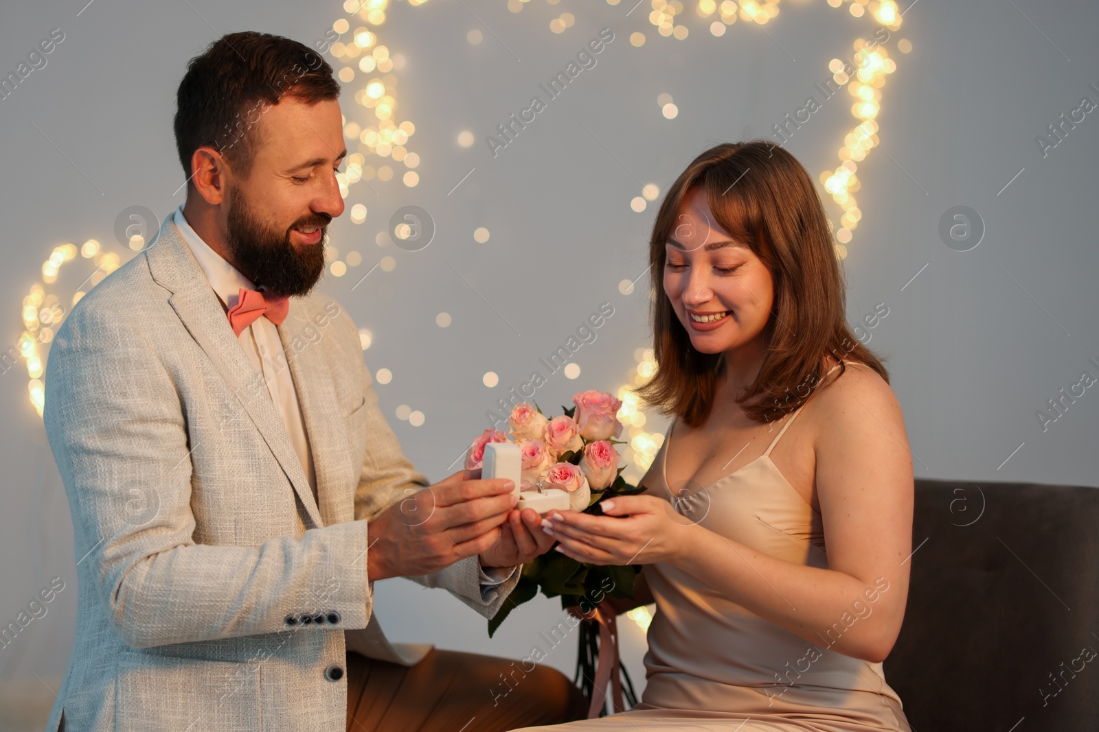 Man with engagement ring making marriage proposal to his girlfriend on light grey background with blurred lights, bokeh effect Photo of Man with engagement ring making marriage proposal to his girlfriend on light grey background with blurred lights, bokeh effect