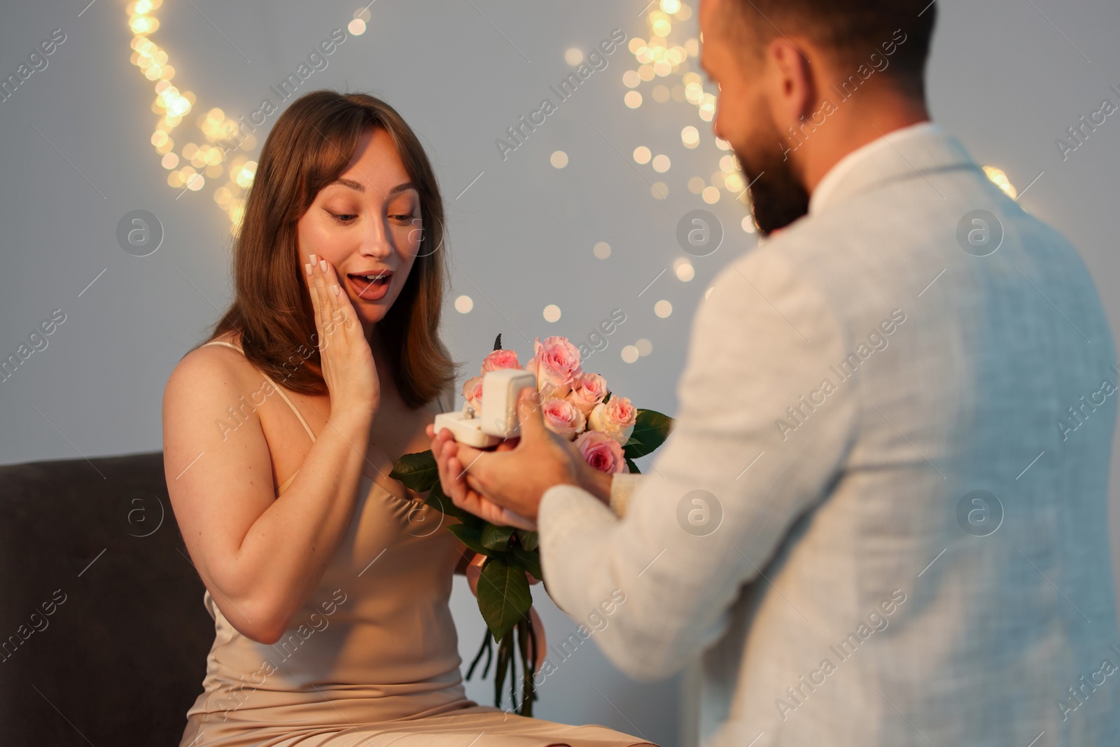 Man with engagement ring making marriage proposal to his girlfriend on light grey background with blurred lights, bokeh effect Photo of Man with engagement ring making marriage proposal to his girlfriend on light grey background with blurred lights, bokeh effect