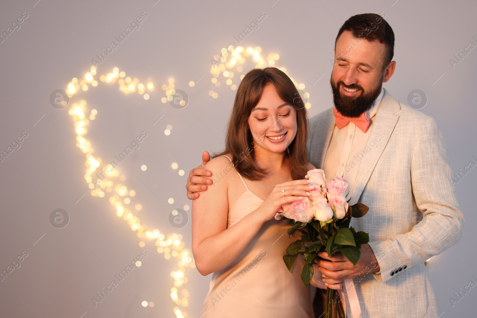 Making marriage proposal. Woman with engagement ring, flowers and her fiance on light grey background, space for text. Bokeh effect Photo of Making marriage proposal. Woman with engagement ring, flowers and her fiance on light grey background, space for text. Bokeh effect
