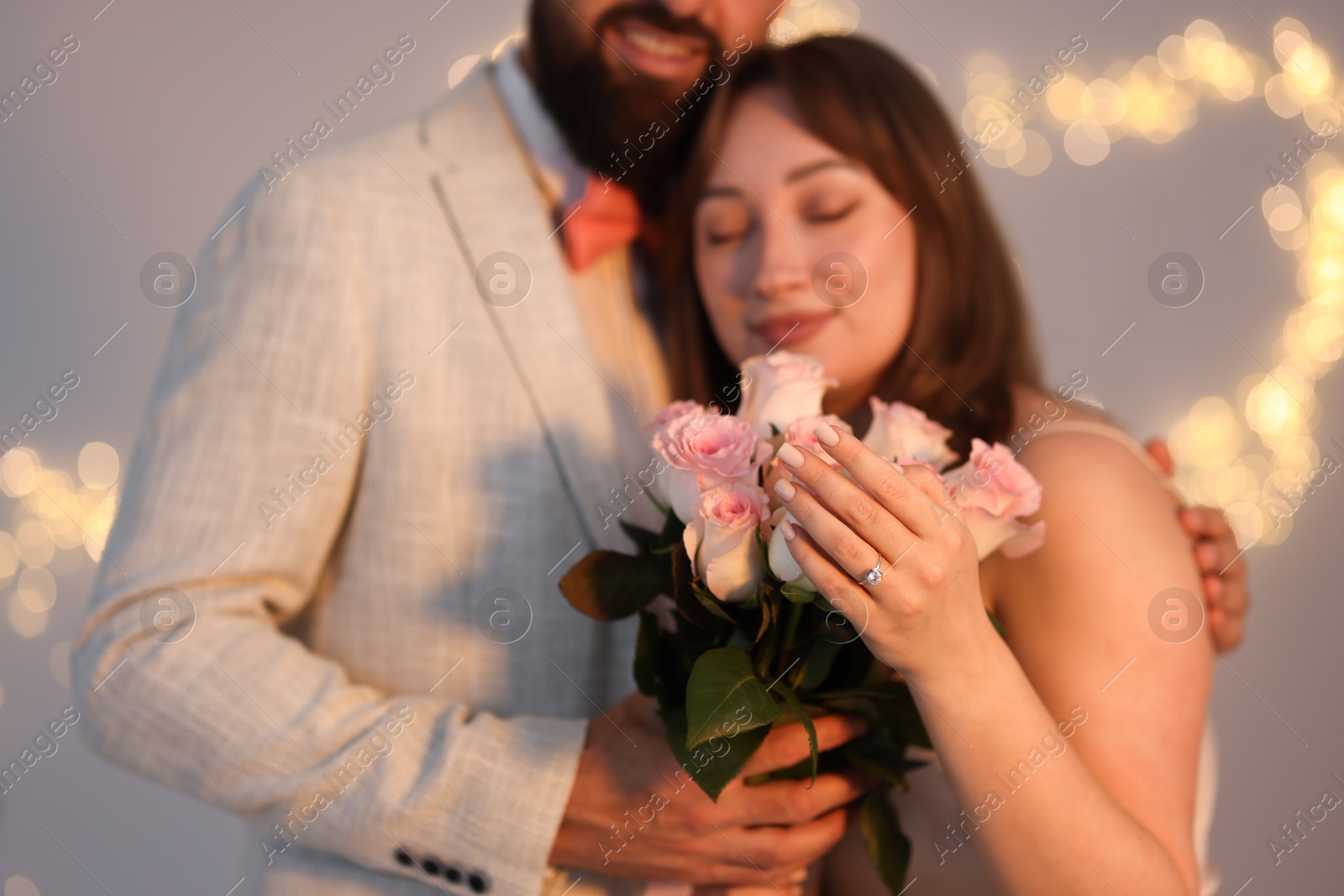 Making marriage proposal. Woman with engagement ring, flowers and her fiance on light grey background, selective focus. Bokeh effect Photo of Making marriage proposal. Woman with engagement ring, flowers and her fiance on light grey background, selective focus. Bokeh effect