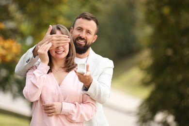 Photo of Man with engagement ring making marriage proposal to his girlfriend outdoors, space for text