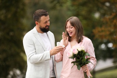 Photo of Man with engagement ring making marriage proposal to his girlfriend outdoors
