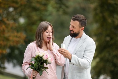 Photo of Man with engagement ring making marriage proposal to his girlfriend outdoors