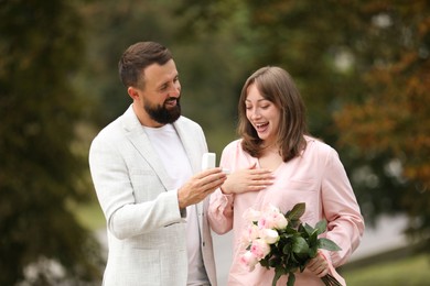Photo of Man with engagement ring making marriage proposal to his girlfriend outdoors