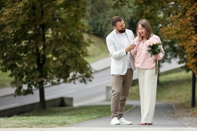 Photo of Man with engagement ring making marriage proposal to his girlfriend outdoors, space for text