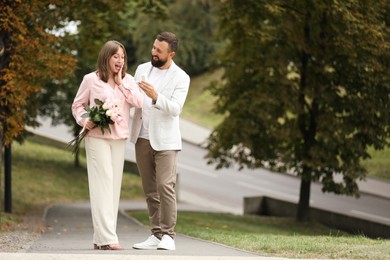 Photo of Man with engagement ring making marriage proposal to his girlfriend outdoors, space for text