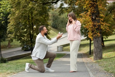 Photo of Man with engagement ring making marriage proposal to his girlfriend outdoors