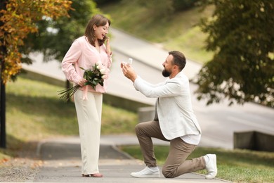 Photo of Man with engagement ring making marriage proposal to his girlfriend outdoors