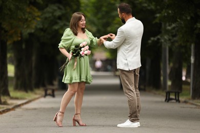 Photo of Making marriage proposal. Man putting engagement ring on his girlfriend's finger outdoors