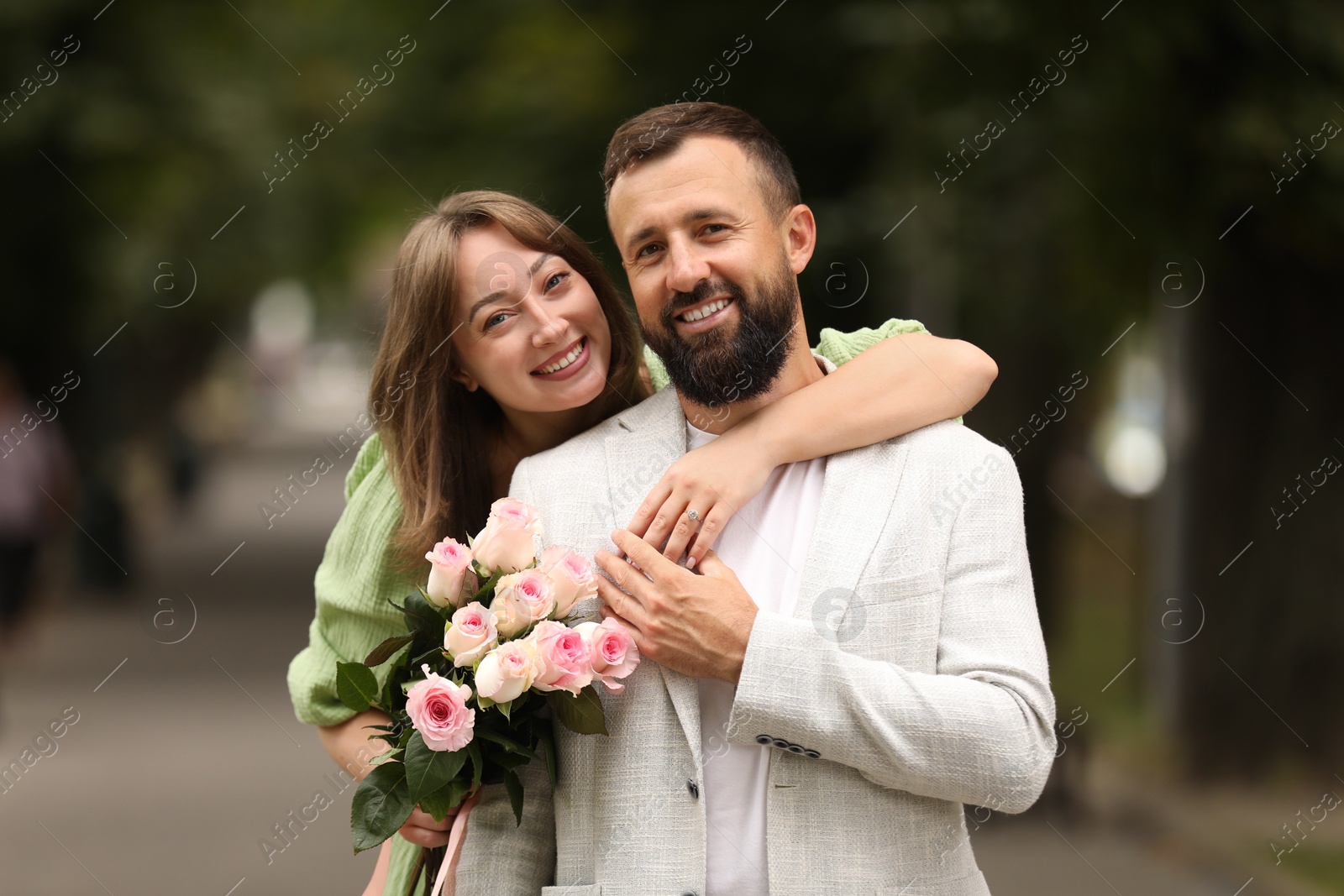 Photo of Making marriage proposal. Woman with engagement ring, flowers and her happy fiance outdoors