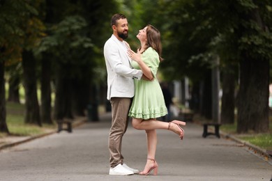Photo of Making marriage proposal. Woman showing engagement ring and hugging her fiance outdoors
