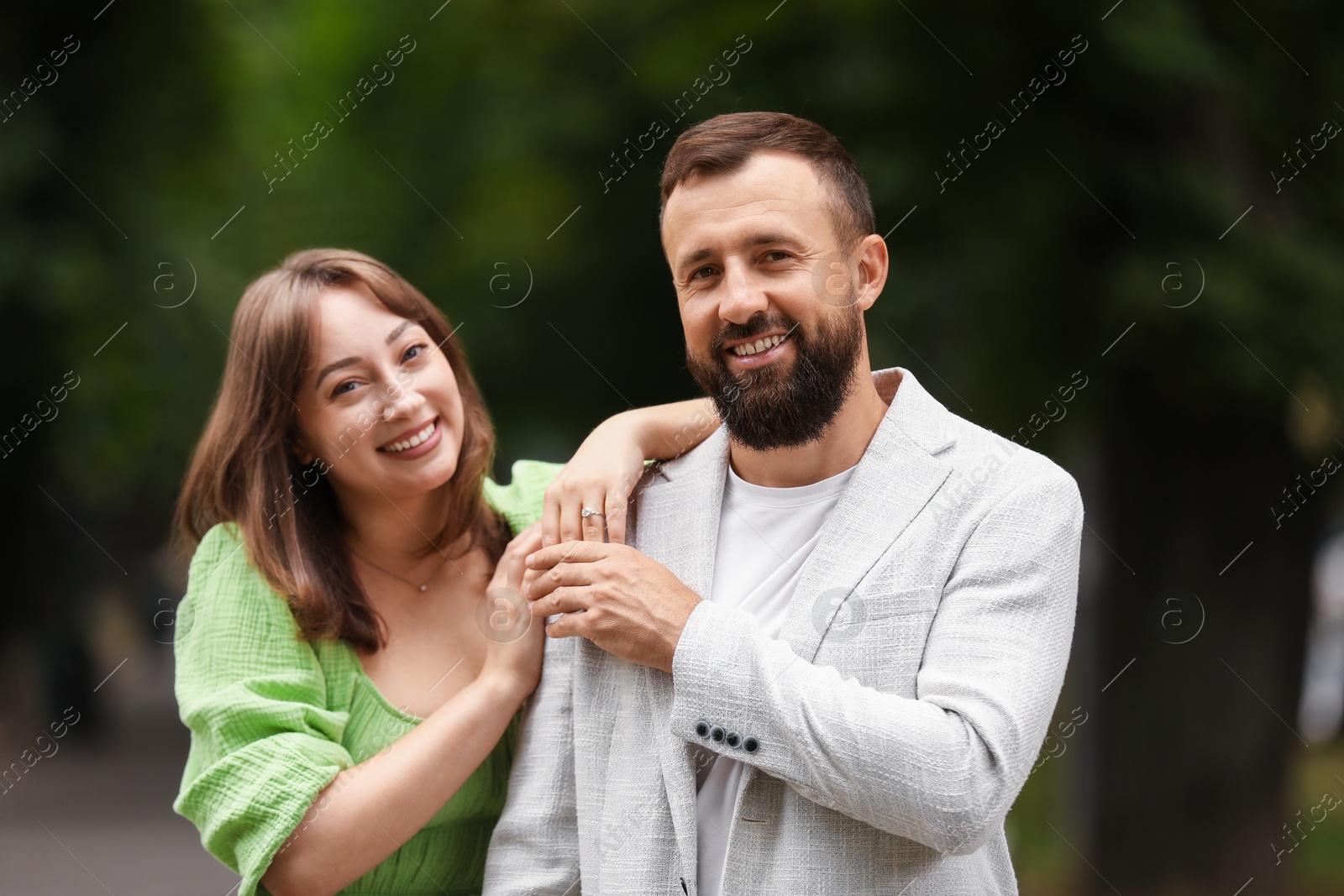 Photo of Making marriage proposal. Woman with engagement ring, flowers and her happy fiance outdoors