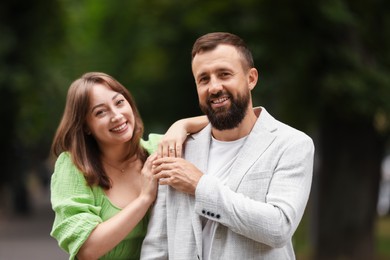 Photo of Making marriage proposal. Woman with engagement ring, flowers and her happy fiance outdoors
