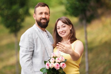 Photo of Making marriage proposal. Woman showing engagement ring and her fiance outdoors