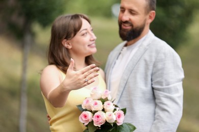 Photo of Making marriage proposal. Woman showing engagement ring and her fiance outdoors, selective focus