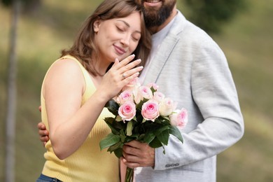 Photo of Making marriage proposal. Woman showing engagement ring and hugging her fiance outdoors, selective focus