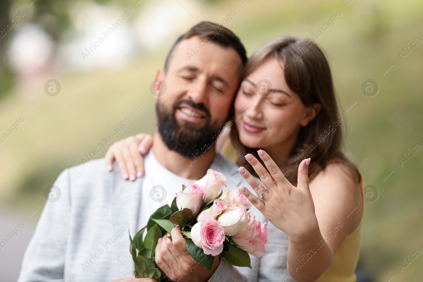 Making marriage proposal. Woman showing engagement ring and hugging her fiance outdoors, selective focus Photo of Making marriage proposal. Woman showing engagement ring and hugging her fiance outdoors, selective focus