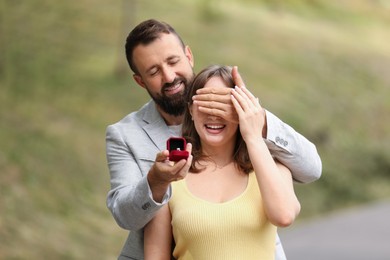 Photo of Man with engagement ring making marriage proposal to his girlfriend outdoors