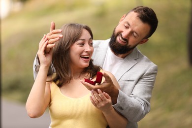 Photo of Man with engagement ring making marriage proposal to his girlfriend outdoors